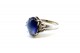 Anel em ouro branco com diamantes (4) em talhe brilhante e safira azul no centro