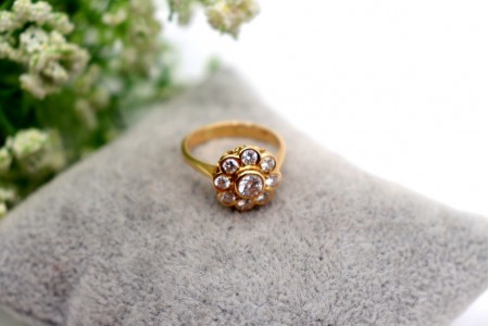 Anel em ouro com nove (9) diamantes em talhe brilhante e em forma de flor.