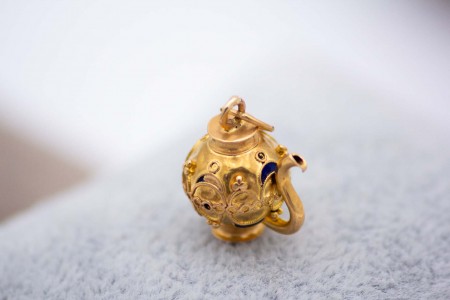 Berloque em ouro em formato de bule.