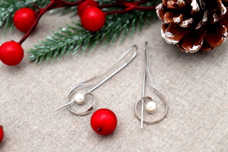 Brincos em ouro branco em forma de clave de sol com pérolas de cultura.