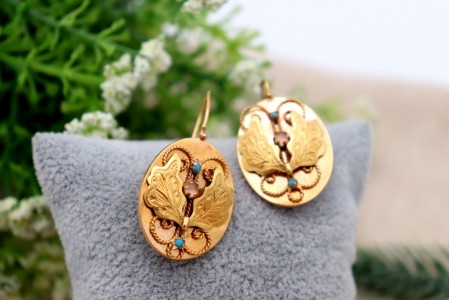 Brincos em ouro em formato ovalizado com aplicações de turquesas.