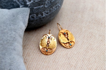 Brincos em ouro em formato ovalizado com aplicações de turquesas.