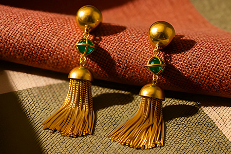 Par de brincos de ouro com cadilhes articulados em suspensão, esmeraldas em formato esférico e fechos omega em ouro branco.