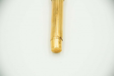 Caneta de tinta permanente em ouro amarelo com frisos al alto.