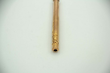 Lapiseira de ouro com motivos florais relevados e argola de suspensão.