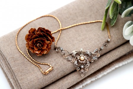 Colar em ouro e prata com lascas de diamante e pérola de cultura no centro.