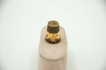 Dedal em ouro amarelo com relevos e friso envolvente