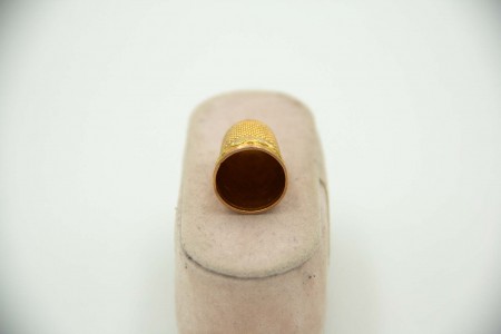 Dedal em ouro amarelo com pequenos relevos na envolvência e coração definido