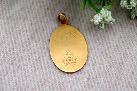 Medalha em ouro com Nossa Senhora orando em vulto perfeito relevado e argola de suspensão.