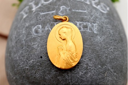 Medalha em ouro com Nossa Senhora orando em vulto perfeito relevado e argola de suspensão.