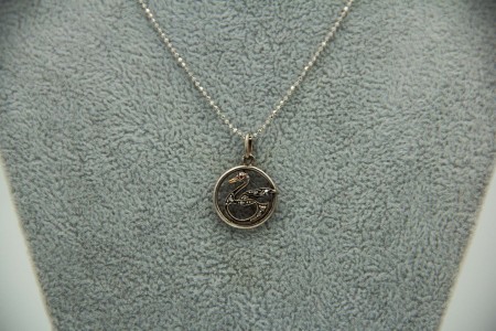 Medalha circular em ouro bicolor com cisne e lascas de diamantes.