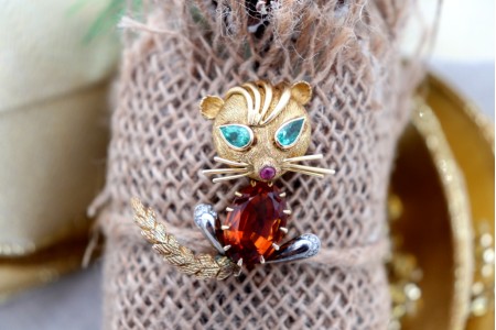 Pregadeira em ouro em forma de gato com lascas de diamantes e esmeraldas