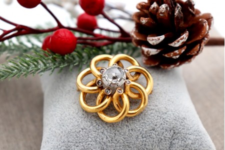 Pregadeira em ouro com laços entrelaçados e diamante