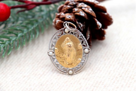 Medalha em ouro bicolor em forma oval com recortes, Nossa Senhora da Conceição relevada, lascas de diamantes e (4) pérolas aplicadas.