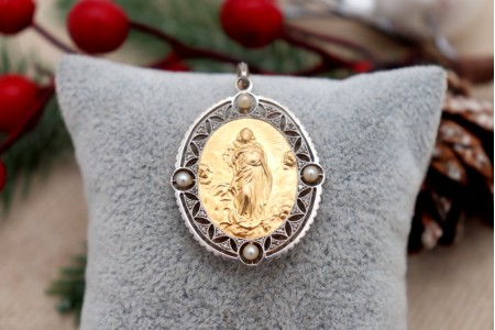 Medalha em ouro bicolor em forma oval com recortes, Nossa Senhora da Conceição relevada, lascas de diamantes e (4) pérolas aplicadas.