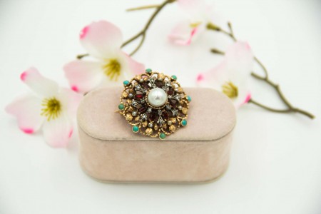 Pregadeira de ouro e elementos em prata com pérola central, turquesas aplicadas e lascas de diamantes.