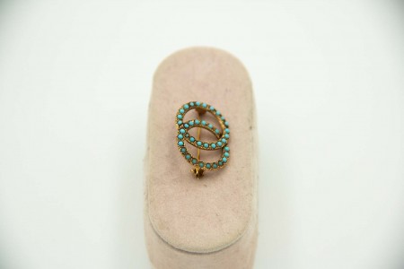 Pregadeira em ouro amarelo em forma de duas alianças e turquesas aplicadas.