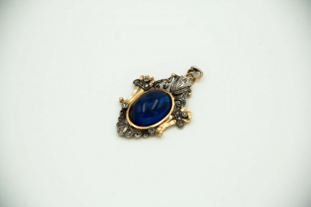 Medalha em ouro e prata com relevos e recortes, cabochão azul em vidro no centro