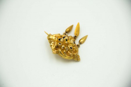 Pregadeira em ouro amarelo com relevos de flores e pingentes articulados.