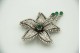 Pregadeira de ouro branco em forma de flor com diamantes (243) e esmeraldas