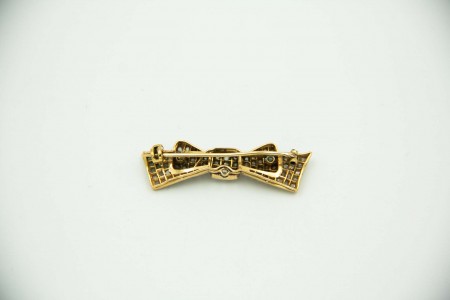 Pregadeira em ouro amarelo e branco em forma de laço com lascas de diamantes