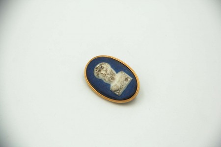 Pregadeira oval com aro em ouro em moldura de figura relevada.