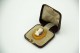 Pregadeira de ouro amarelo de formato oval com friso perlado envolvendo camafeu