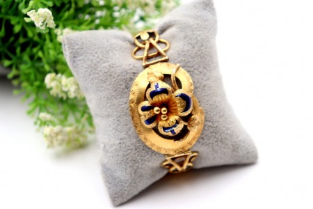 Pulseira em ouro com relevos e aplicações com flor no centro esmaltada