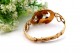 Pulseira em ouro com relevos e aplicações com flor no centro esmaltada