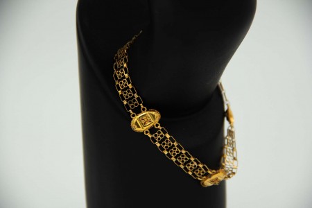 Pulseira de ouro amarelo com relevos e elos articulados.