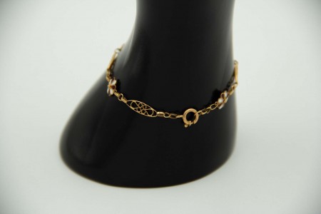 Pulseira de ouro amarelo recortada, elos articulados e flores esmaltadas.
