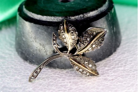 Pregadeira em ouro e prata com forma de flor com lascas de diamantes.