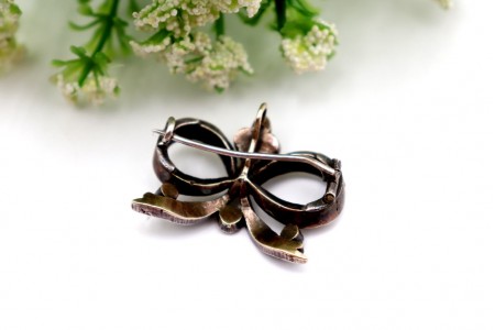 Pregadeira em ouro e prata em forma de laço com lascas de diamantes e esmeraldas