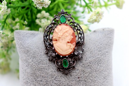 Pregadeira em prata recortada com lascas de diamantes e duas esmeraldas envolven