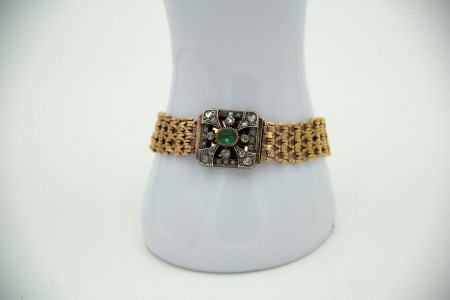 Pulseira de ouro com elos articulados, esmeralda e diamantes aplicados no fecho.