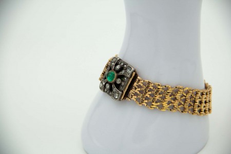 Pulseira de ouro com elos articulados, esmeralda e diamantes aplicados no fecho.