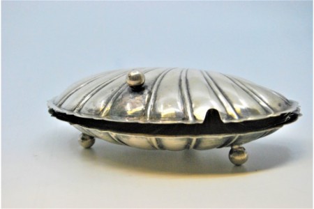 Manteigueira de prata em forma de dupla concha e assente sobre três pés.