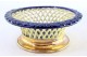 Aneleira de porcelana recortada em tons de azul e creme, com base circular em prata dourada.