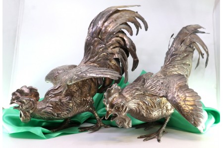 Par de galos de luta em prata com relevos e aplicações.