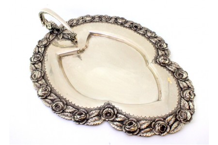 Bandeja de prata com pega, motivos florais relevados e asa em forma de dragão expelindo fogo.