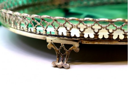 Bandeja em prata com gradinha e assente em quatro pés recortados.