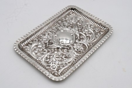 Bandeja rectangular em prata com motivos vegetalistas relevados e figuras alegóricas em alto relevo.