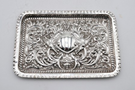 Bandeja rectangular em prata com motivos vegetalistas relevados e figuras alegóricas em alto relevo.