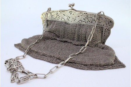 Bolsa de mão em prata recortada com motivos florais gravados, interior forrado a cetim e corrente em malha cadeado.