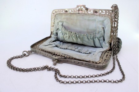 Bolsa de mão em tecido bordado com figura feminina suportada por arco em prata recortada, motivos florais, corrente em malha cordão e interior forrado com duas bolsas.