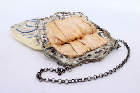 Bolsa de mão com arco em prata recortada suportando o tecido da bolsa