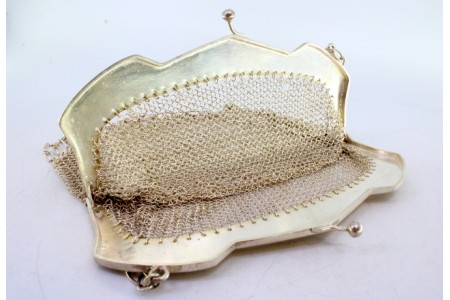 Bolsa de mão em malha de prata com fantasias, gravados de motivos florais no arco, franjas em suspensão e corrente de malha cadeado.