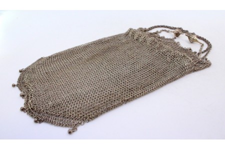  Bolsa de mão tipo saco em malha dupla de prata com franjas suspensas e corrente em malha corda com pingentes em forma de piões.