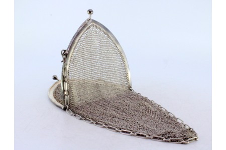 Bolsa de mão em malha de prata com franja suspensa, arco liso ao estilo gótico e corrente cadeado.