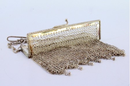  Bolsa de mão em malha de prata com franjas esféricas, arco frisado e corrente com torcidos.